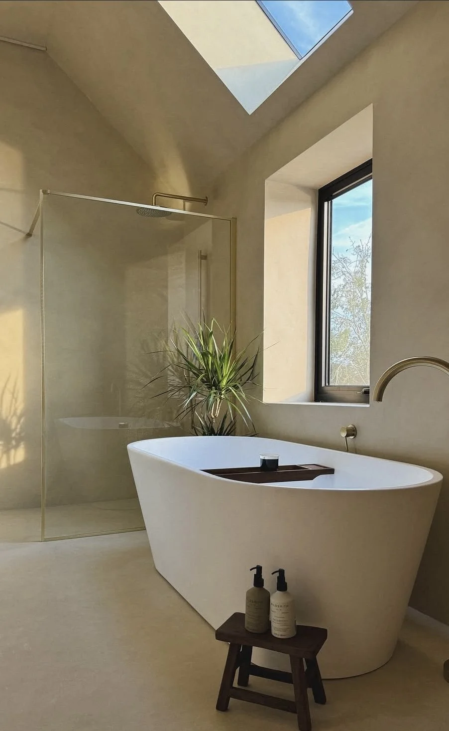 Architectural bathroom with seamless walls and floor, a freestanding bath and natural daylight